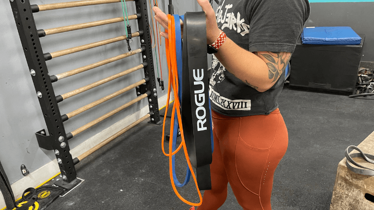 A woman holds up an assortment of Rogue Resistance Bands.