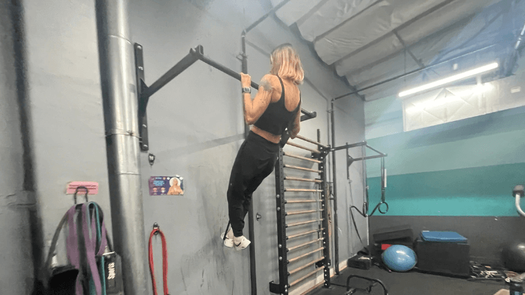 A woman does pull-ups with the Rogue Resistance Bands assisting.