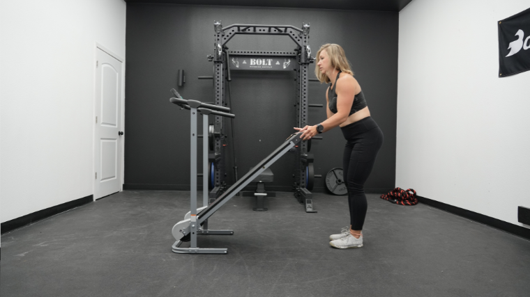 A woman unfolds a manual treadmill.