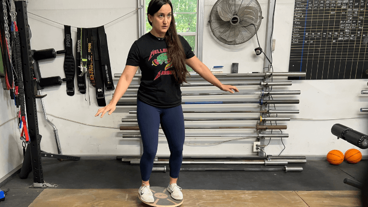 A woman balances on the top of the Yes4All Wooden Wobble Balance Board.