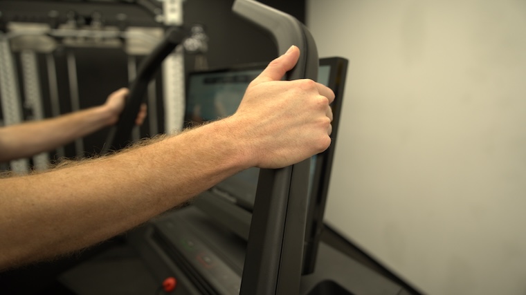 Our tester grabbing the handrails of the NordicTrack X24 treadmill