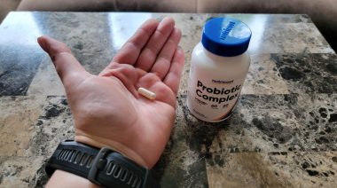A woman's hand holding a capsule of Nutricost Probiotic Complex