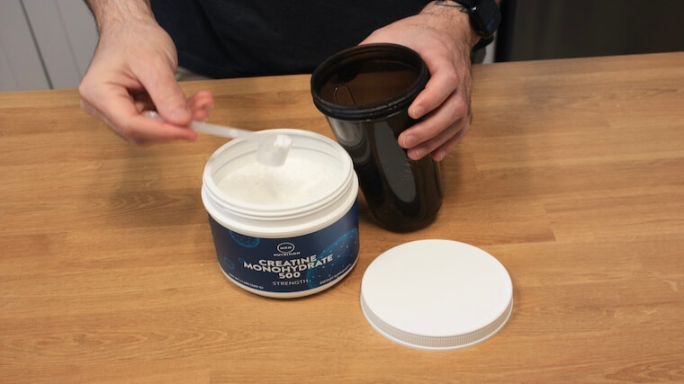 Our tester grabbing a scoop of MRM Nutrition Creatine Monohydrate