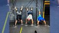 Three CfrossFit athletes doing handstands against a wall.