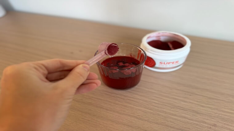 Our tester adding a scoop of HumanN SuperBeets powder to a glass of water
