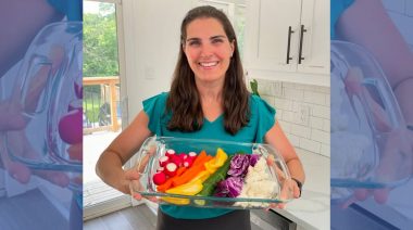 A person holds a tray of rainbow-colored foods