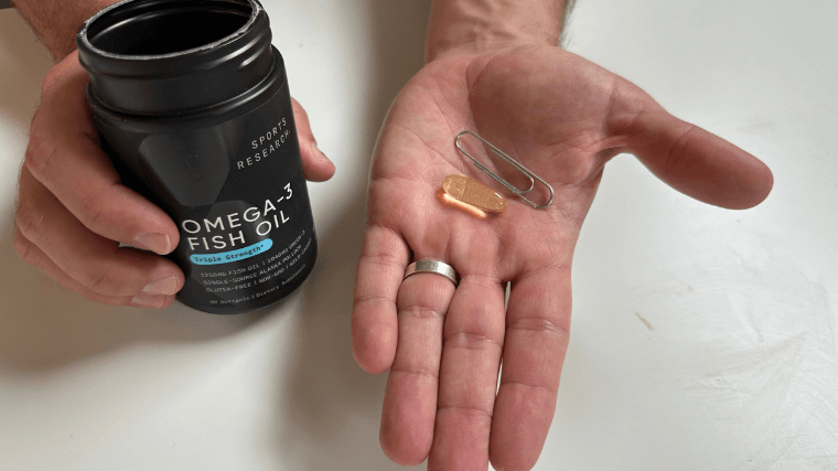 Our tester comparing the size of a Sports Research Omega-3 capsule to a paper clip