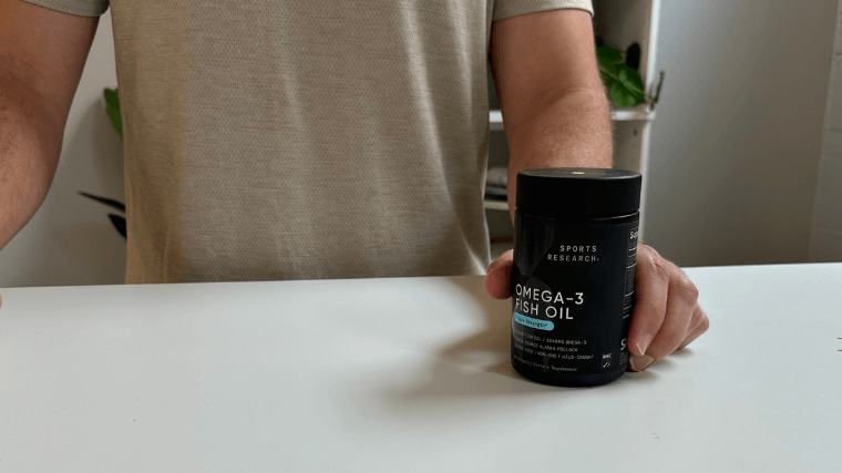 Our tester holding a container of Sports Research Omega-3 fish oil capsules
