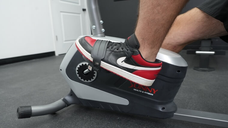 Our tester's feet resting on the Sunny Health and Fitness Essential Recumbent Bike's pedals